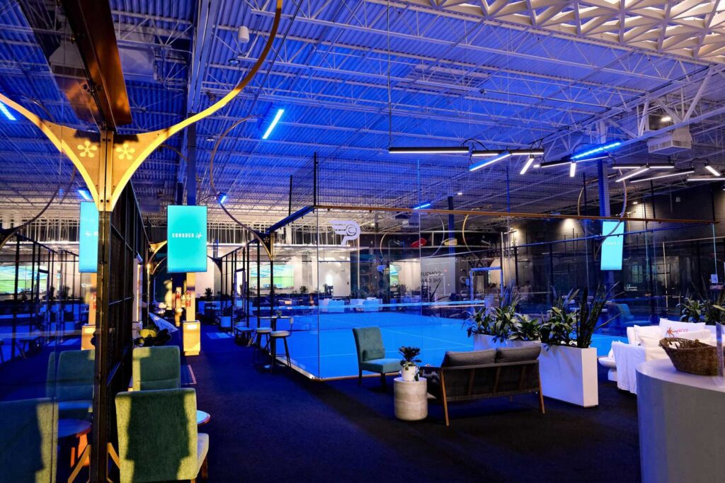 Interior view of Conquer Padel Tempe club at night, showing modern lounge areas and illuminated courts